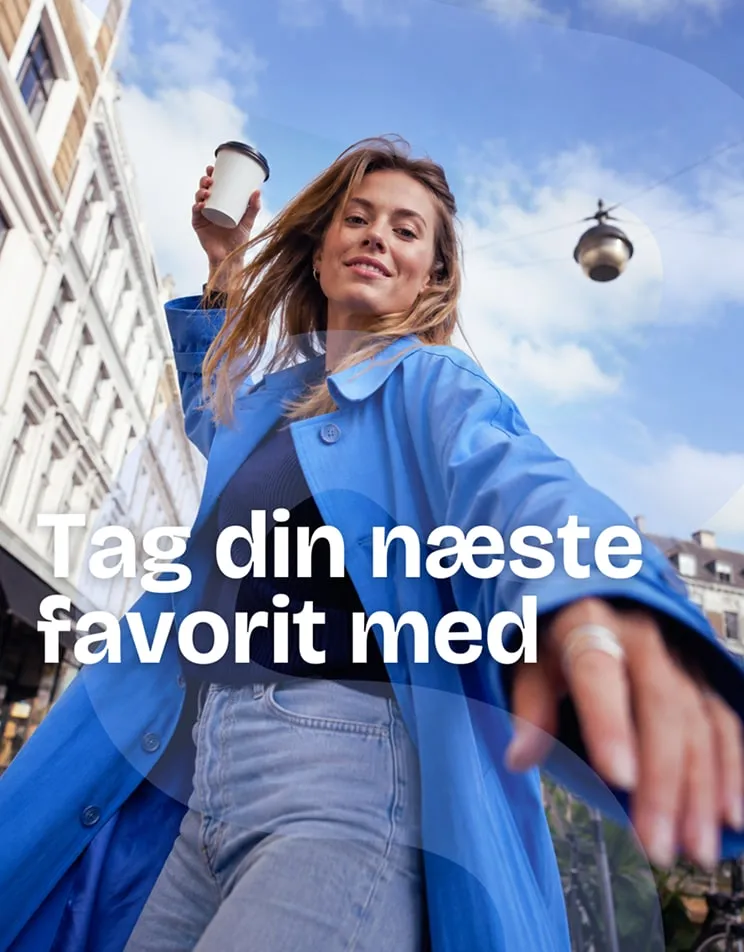 Kampagnebillede af en kvinde i blå frakke med en kaffekop i byen. Tekst: Tag din næste favorit med.
